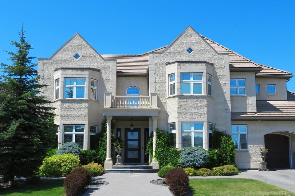 Large modern home with expansive windows and landscaped grounds