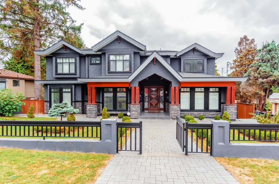 Two-story craftsman-style house with a stone walkway and front fence